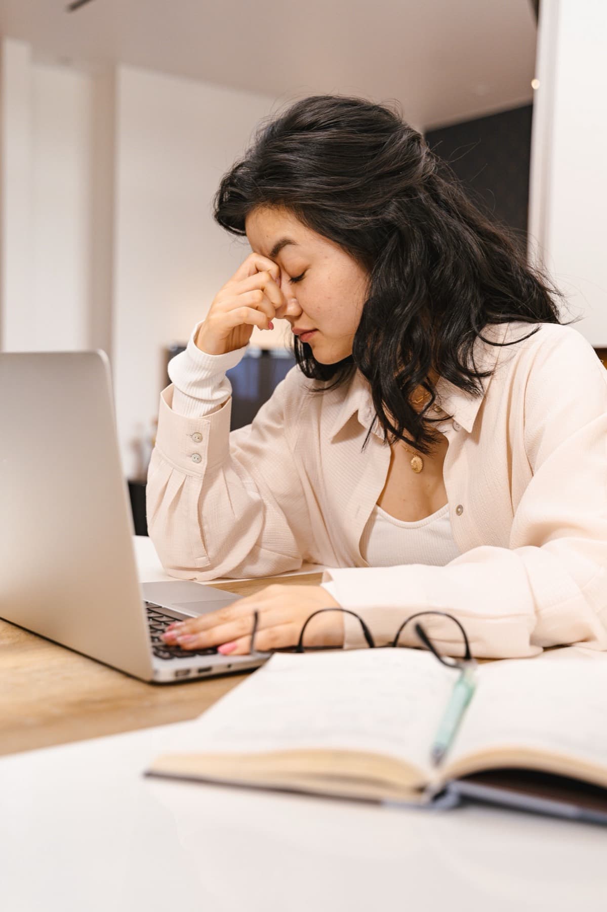 Profesional con gesto de agotamiento frente al computador y un cuaderno abierto
