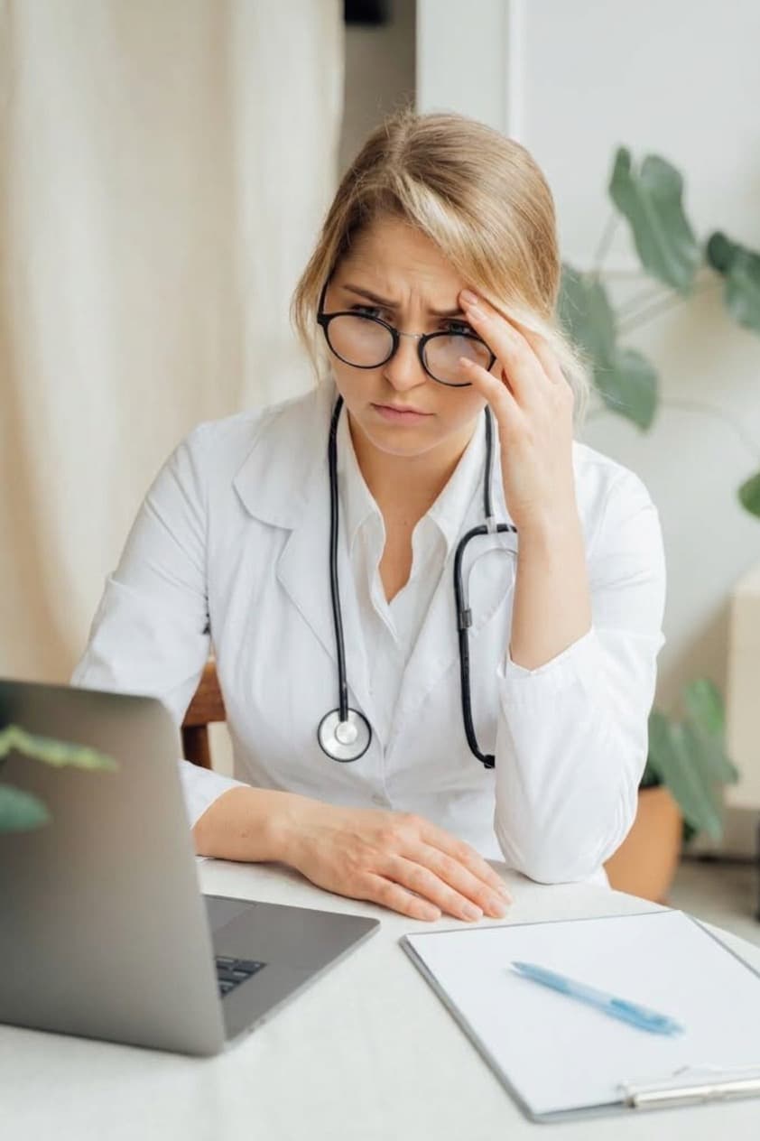 Profesional de la salud con gesto de preocupación frente al computador